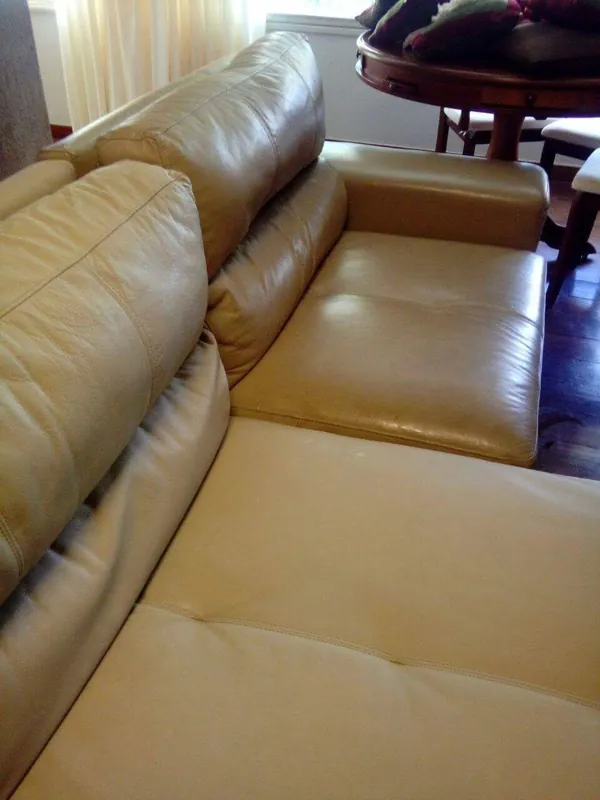 Sofá de couro com o assento do fundo ainda escuro e brilhante e o assento da frente já limpo e hidratado